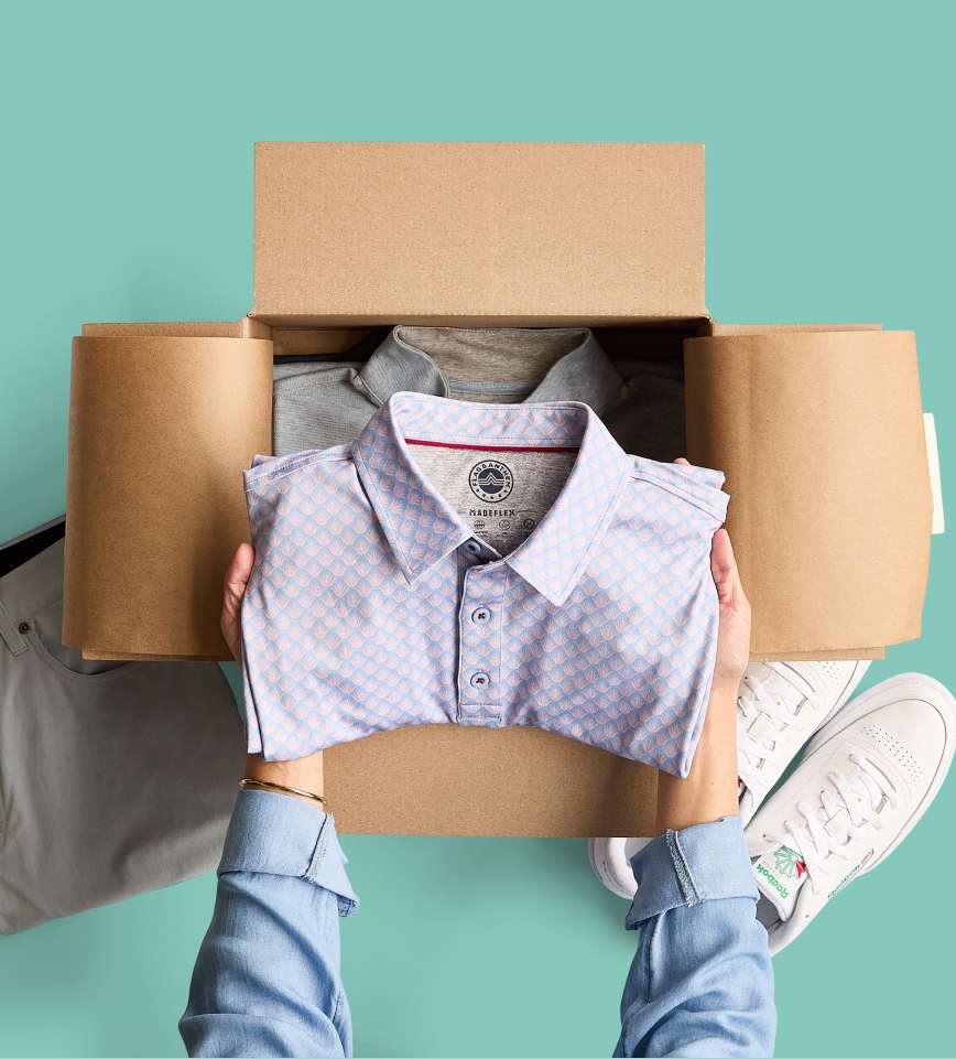 Hands pulling out folded pants from a Stitch Fix delivery box—men’s clothing subscription with free shipping and returns.