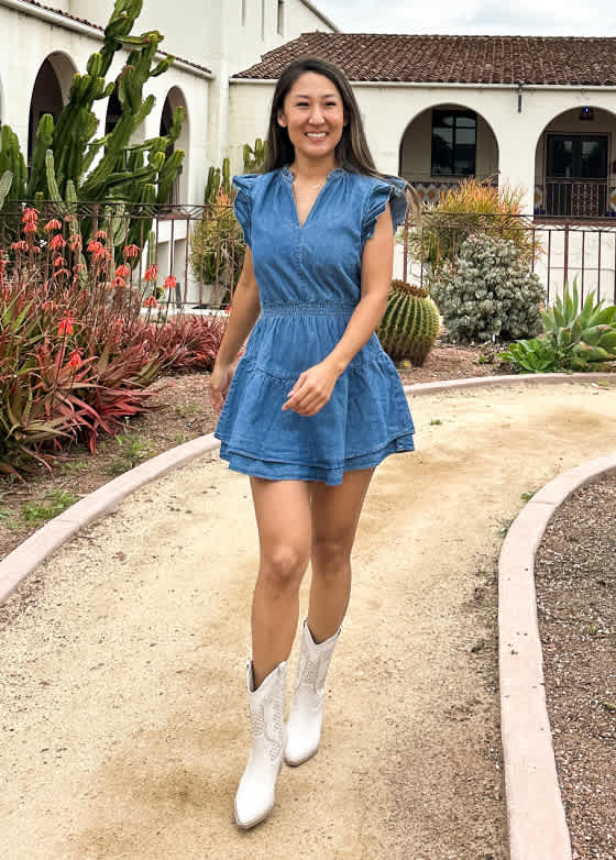 Model wearing Stitch Fix women’s clothing, including: a short-sleeve denim mini dress with a zip-front detail, paired with white ankle boots.