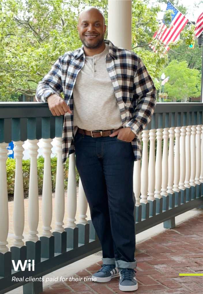 Model wearing Stitch Fix men’s clothing, including: black-and-white plaid overshirt, henley tee, dark jeans, blue sneakers.