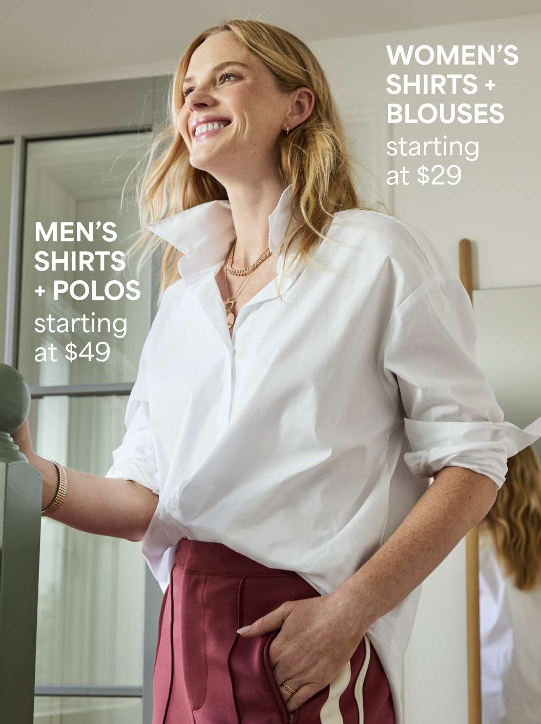 Women’s button-downs – A woman in a crisp white button-down shirt and maroon pants smiles while standing indoors. Text reads “Women’s shirts + blouses starting at $29. Men's Shirts & Polos starting at $49”