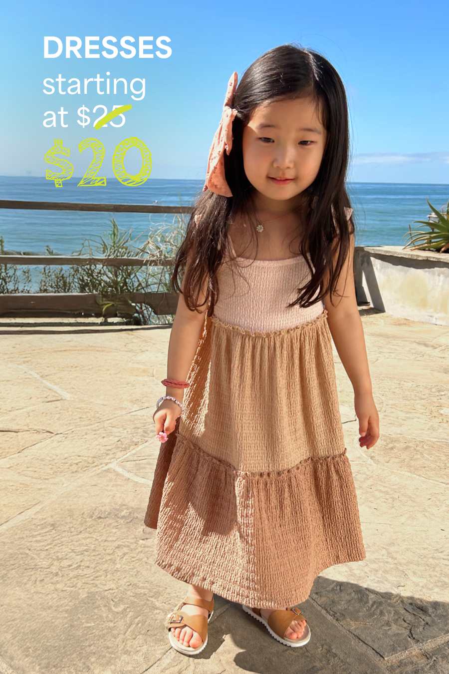 Girl in Stitch Fix: peach tiered dress and sandals, near ocean. Text: “DRESSES starting at $20.”