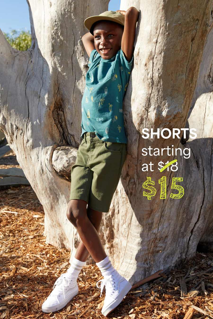 Boy in Stitch Fix: green hoodie and tan shorts, climbing a tree. Text: “SHORTS starting at $15.”