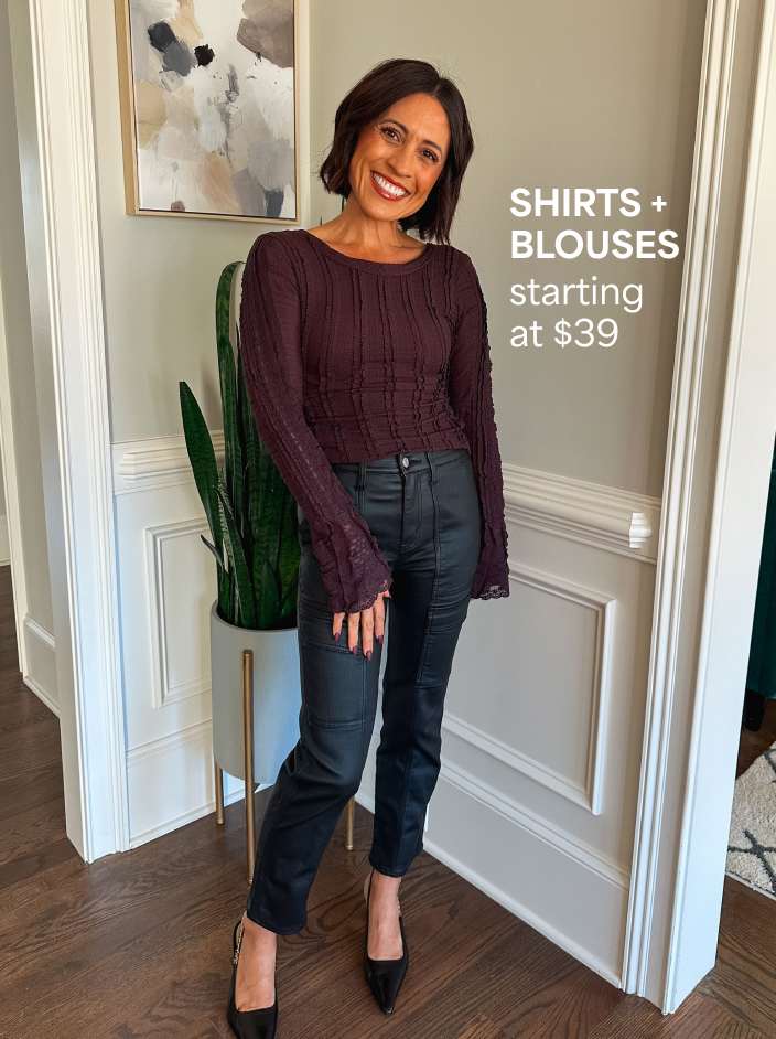 Shirts + Blouses starting at $39. The image shows a petite woman in a burgundy long-sleeve top, black pants and black high heels