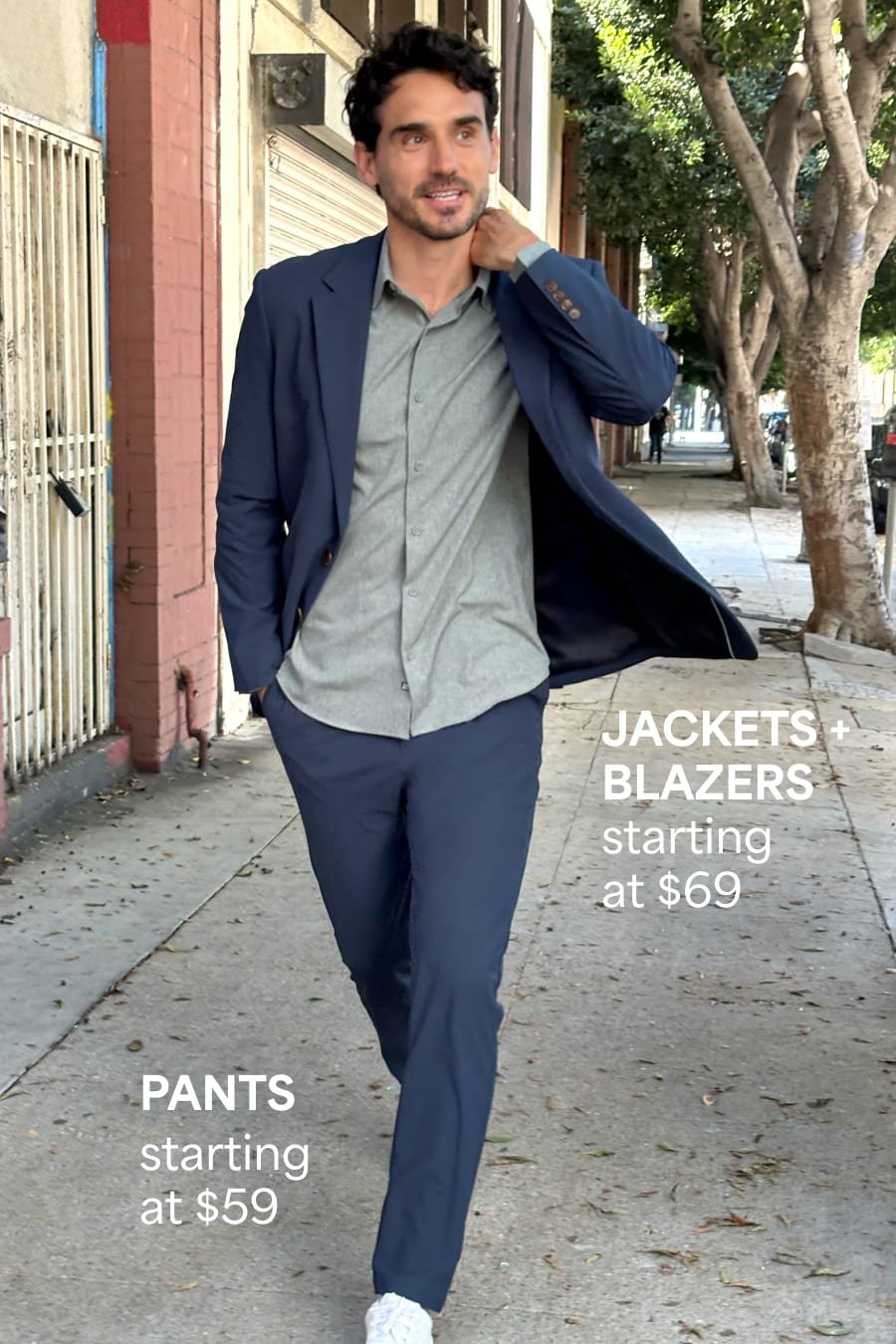 A man with brown hair wears a navy blazer, navy pants and a lighter blue patterned button up. Jackets + Blazers starting at $69. Pants starting at $59.