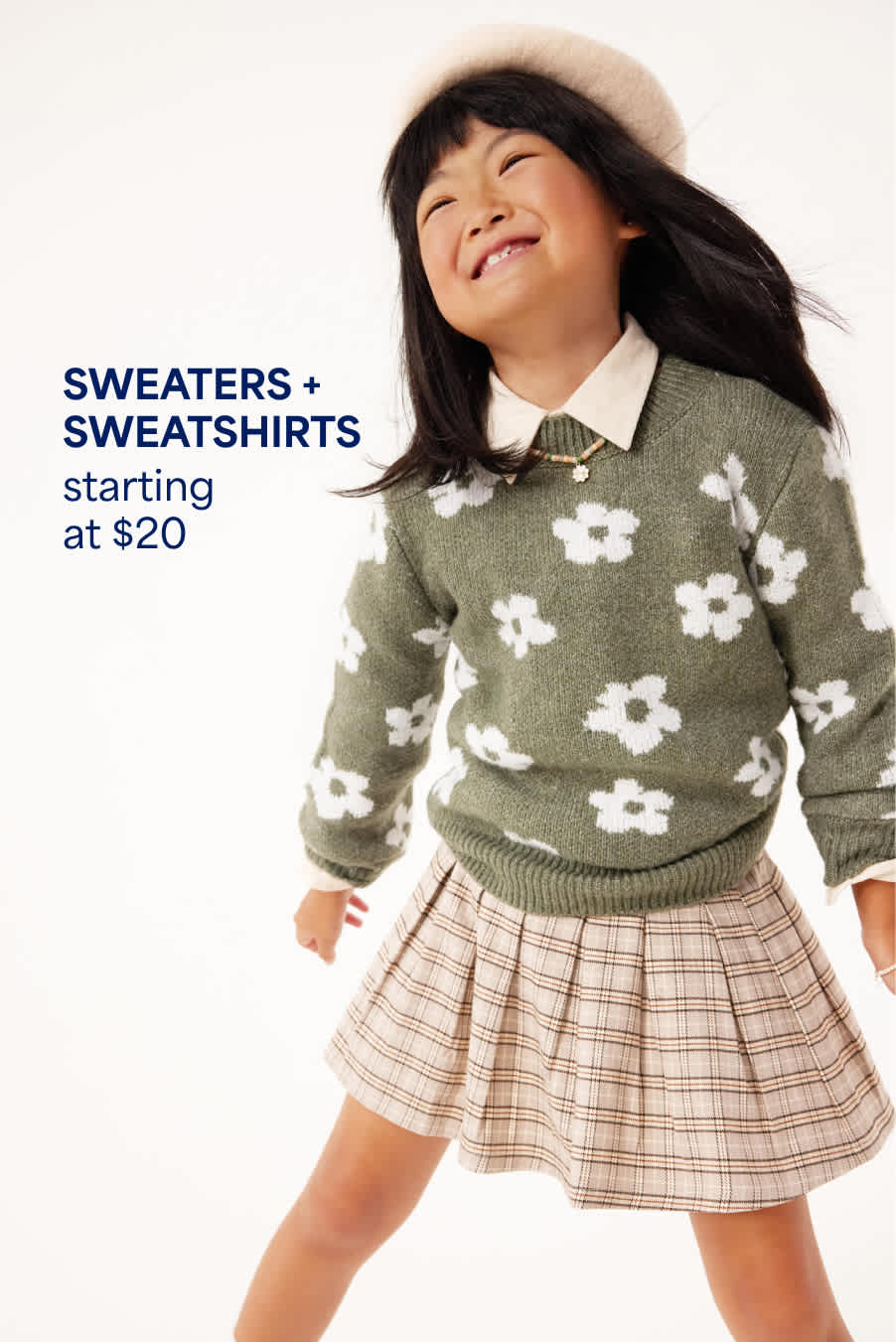 A girl wears a green sweater with white flowers over a collared shirt, paired with a beige plaid skirt and cream lace-up boots. Sweaters & Sweatshirts starting at $20