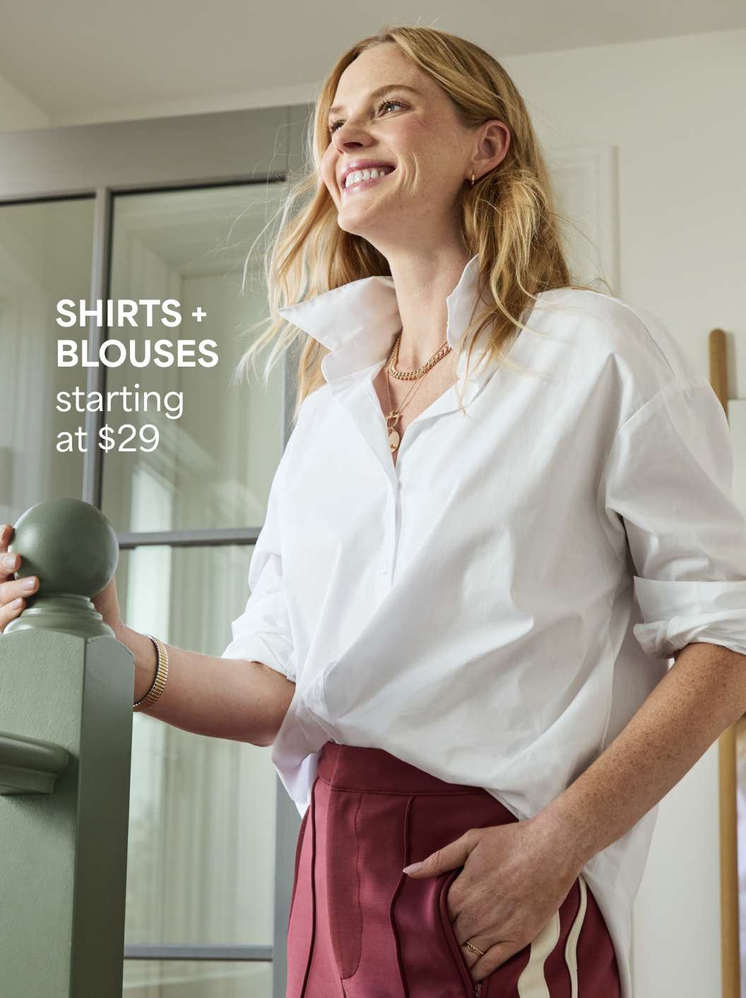 A Stitch Fix woman model posing and wearing a white button-down shirt. Shirts + blouses starting at $29