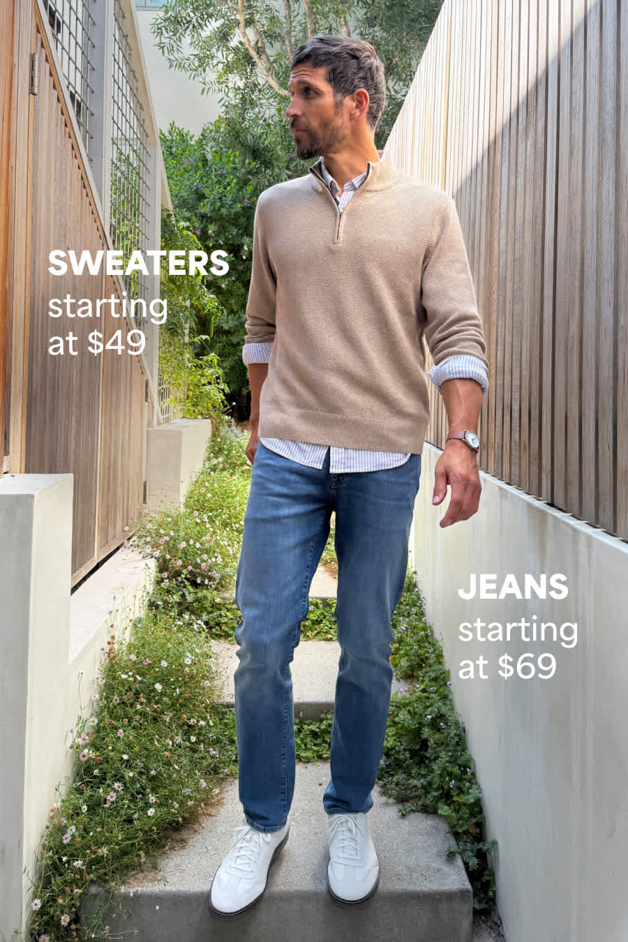Stitch Fix male model posing outdoors wearing a tan quarter-zip over a button-down, blue jeans and white sneakers. Text overlay on image reads “Sweaters starting at $49” and “Jeans starting at $69”