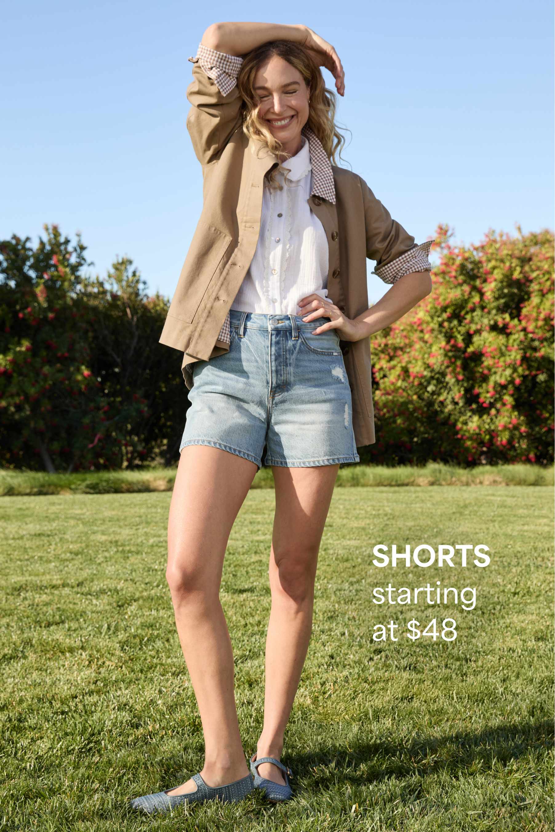 A woman Stitch Fix model poses in a grassy field in denim shorts. A text overlay reads: “SHORTS - starting at $48”.