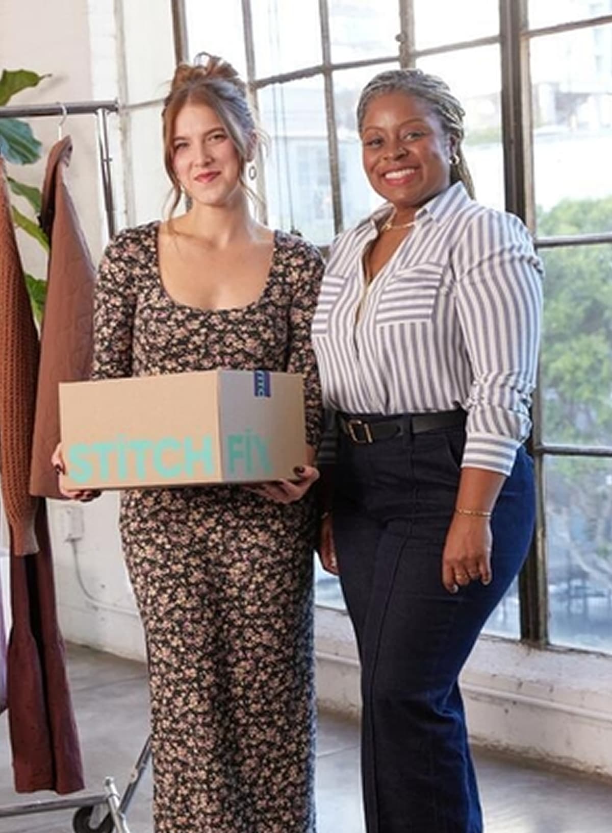 Two women Stylists, one in black floral dress, one in striped blouse and navy pants, holding Stitch Fix box