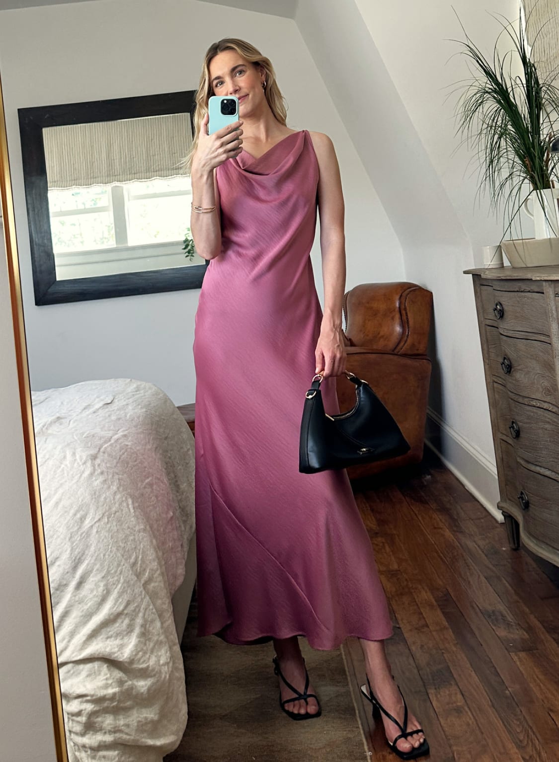 Woman in pink satin maxi dress and black heels taking mirror selfie indoors