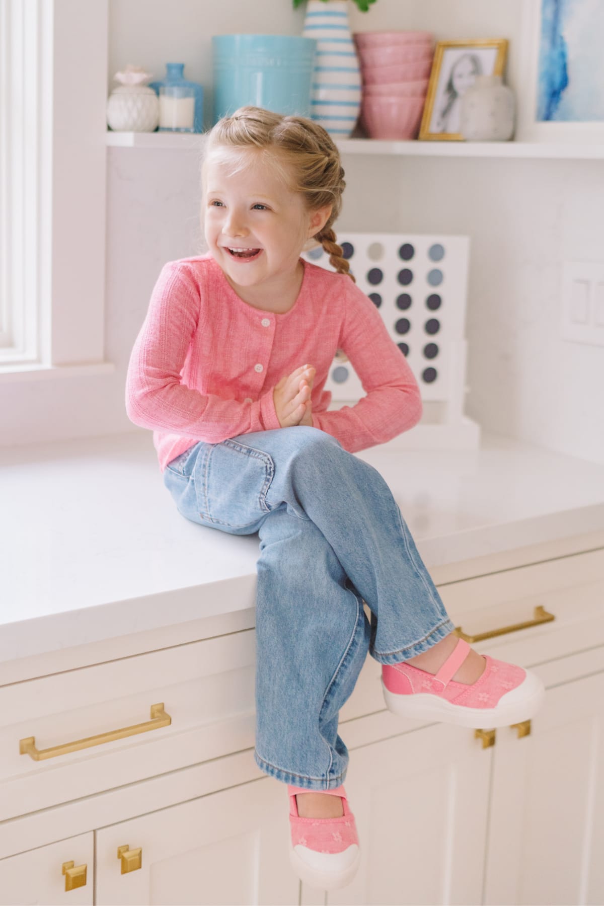 Model wearing Stitch Fix kids’ clothes including a pink cardigan, light blue jeans, and pink shoes.