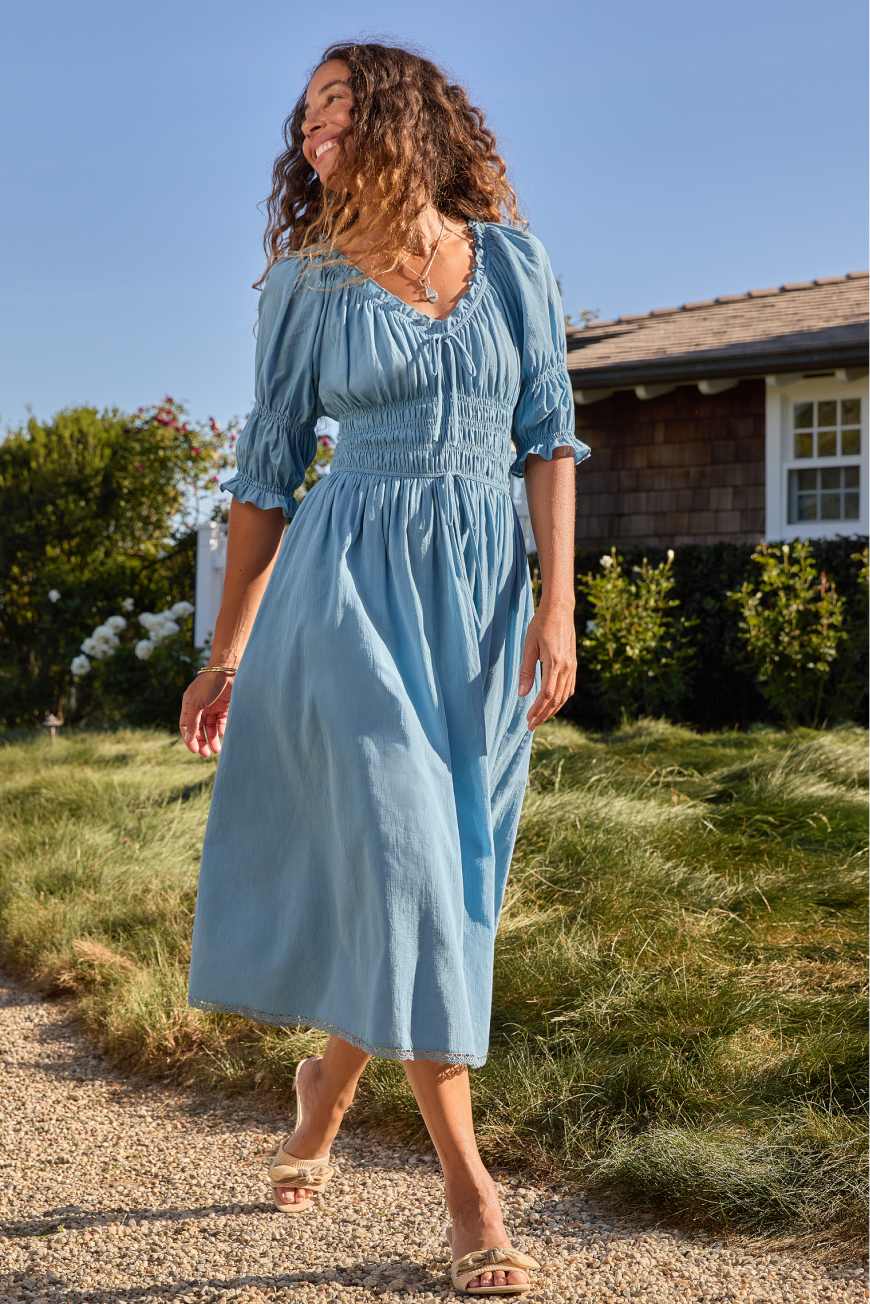 Model wearing Stitch Fix women’s clothing including blue dress, white jean jacket and yellow purse.