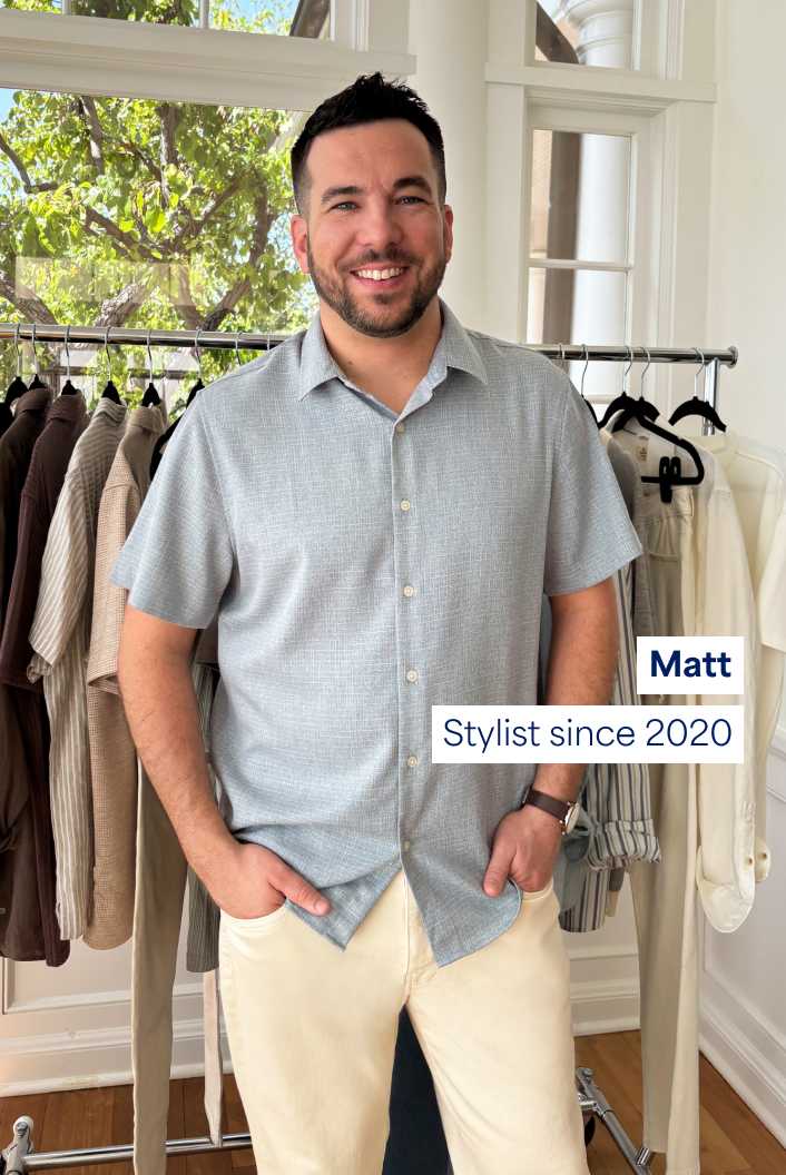 Matt, Stylist since 2020. Matt stands in front of a rack of clothing, including collared shirts and slacks.