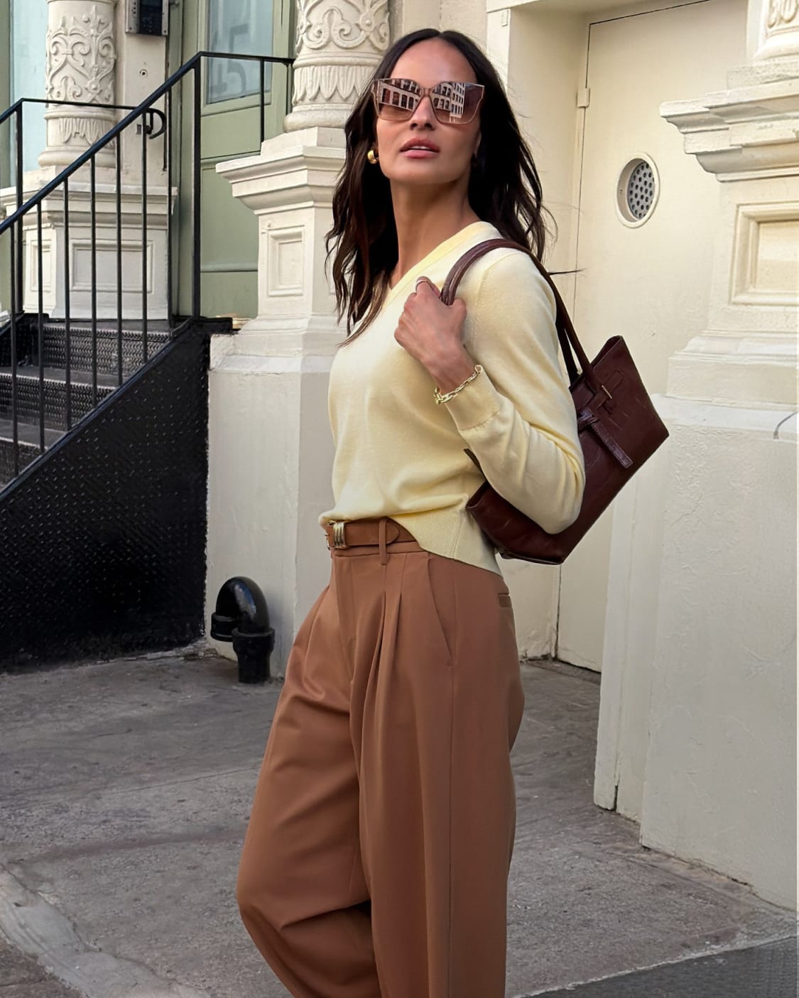 Side-by-side of a woman in yellow sweater carrying brown bag and a woman in brown cardigan with dark pants