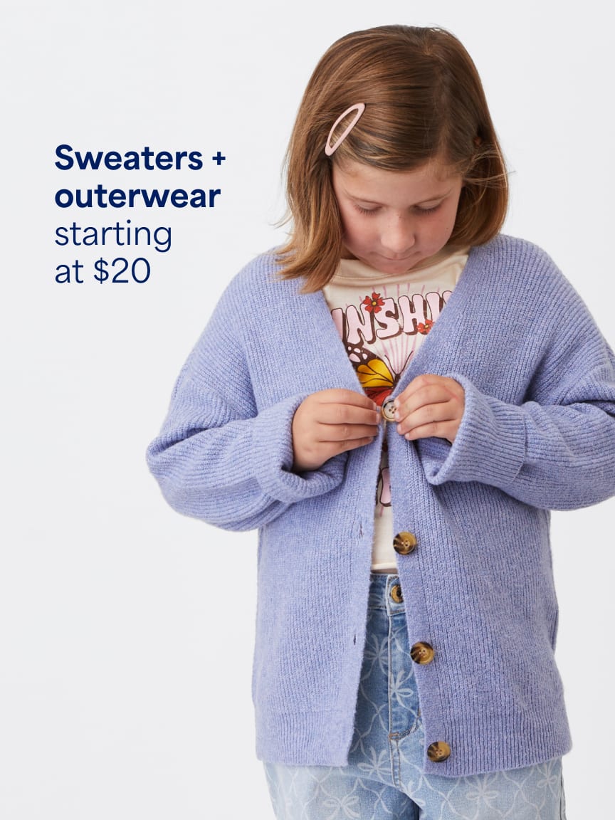 Girl buttoning a light purple knit cardigan over a graphic t-shirt and light blue jeans. Text: Sweaters and outerwear starting at $20