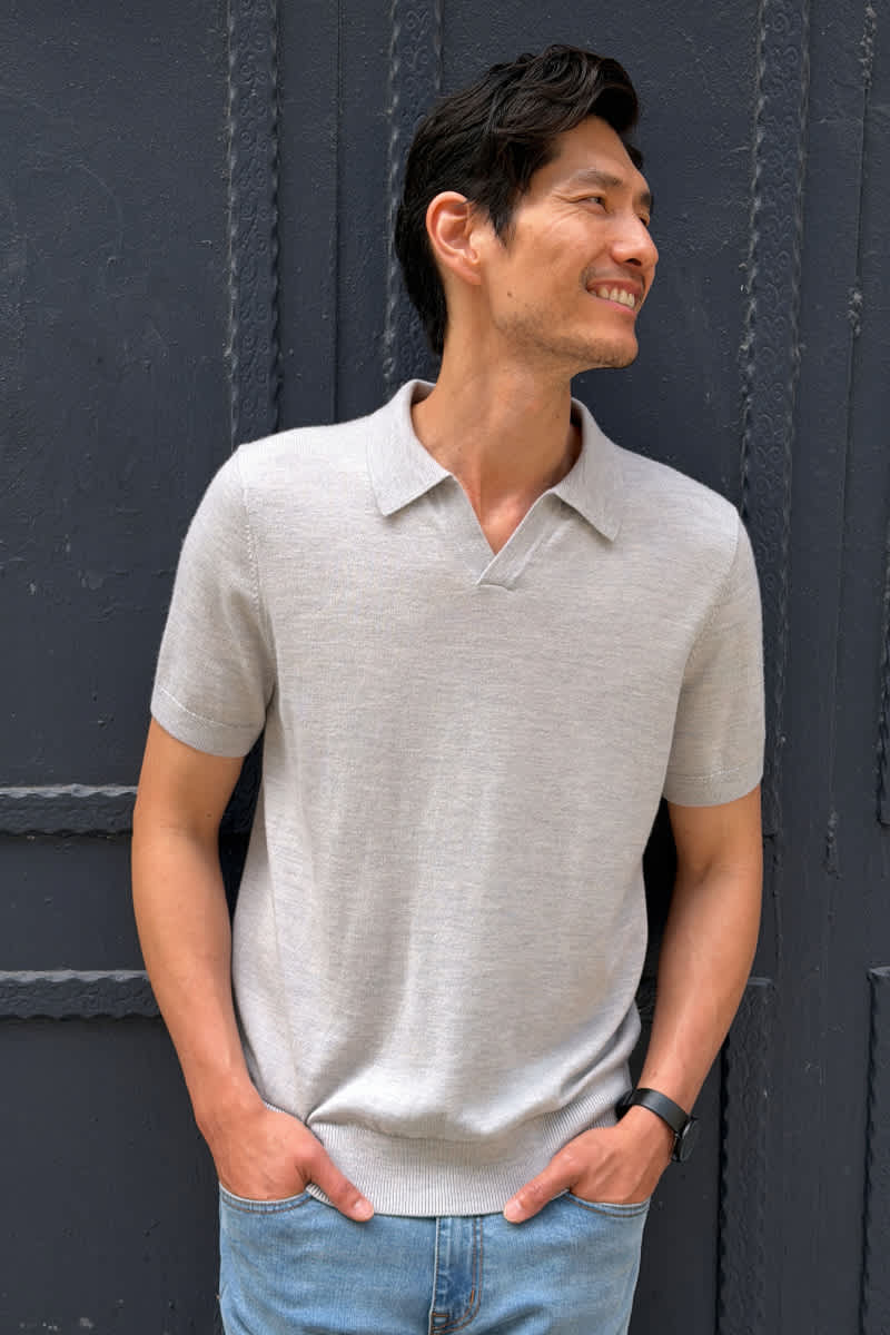 Model wearing Stitch Fix men's clothes including a light gray short-sleeve polo sweater, light wash jeans, and a black watch.