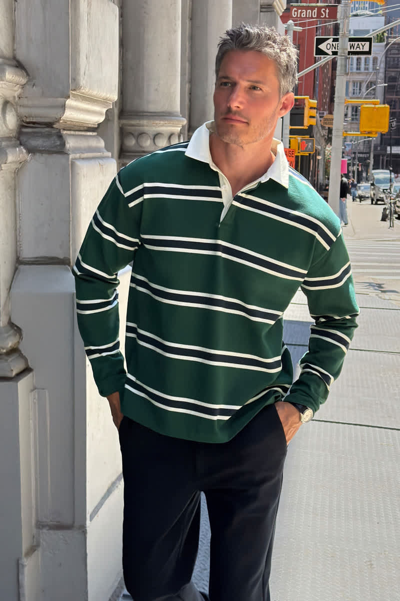 Model wearing Stitch Fix men's clothes including a green striped rugby shirt, navy trousers, and a silver watch.