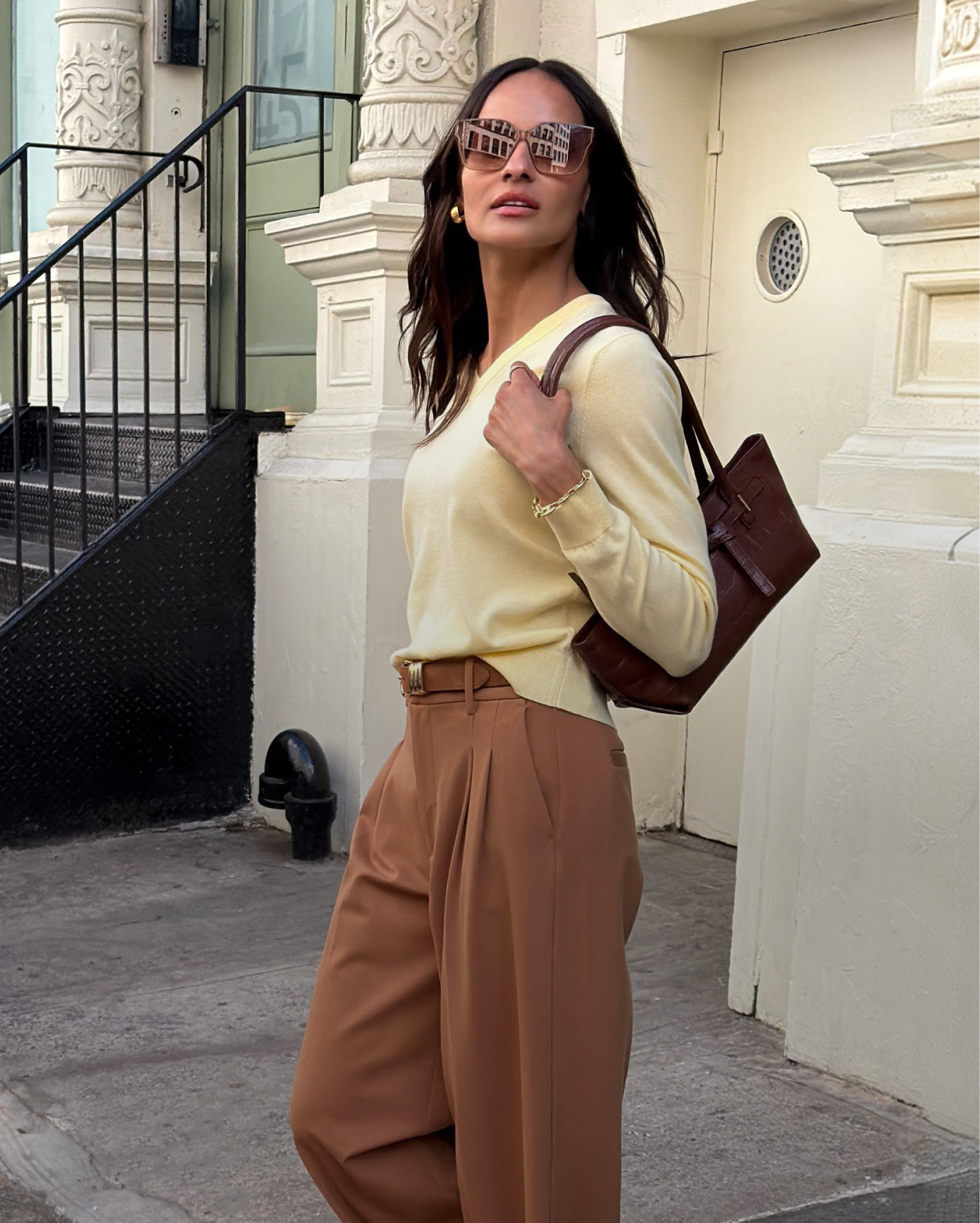 Side-by-side of a woman in yellow sweater carrying brown bag and a woman in brown cardigan with dark pants