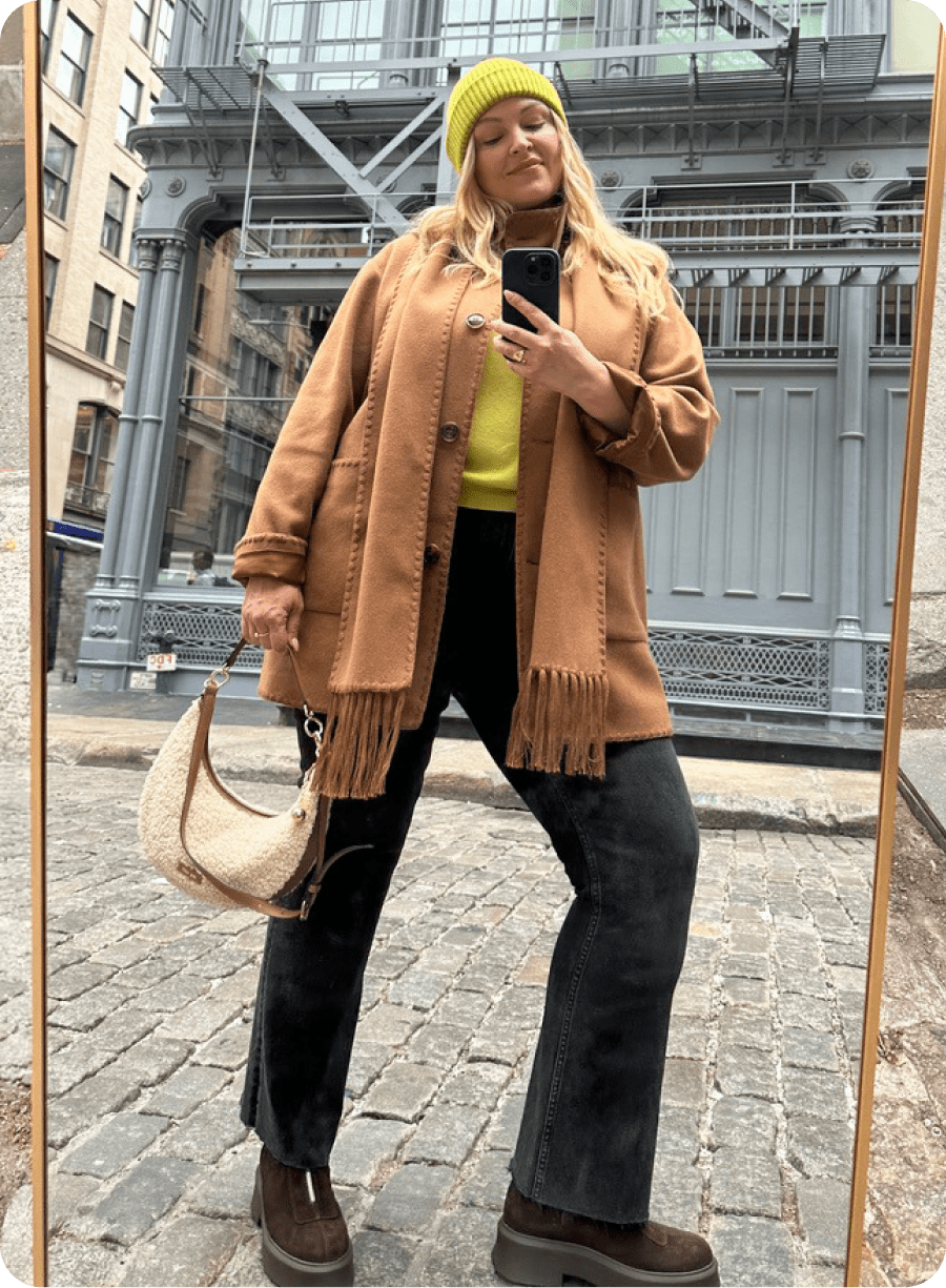 Woman in navy vest, cream midi skirt, black flats, carrying black woven bag