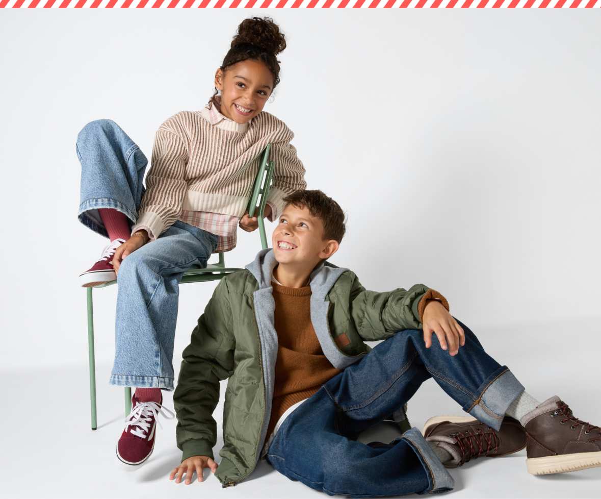 A split children's fashion image featuring two smiling kids walking together outdoors in winter coats and sweaters on the left, and two kids playing with Stitch Fix gift boxes indoors on the right—one wearing a light purple party dress holding a box overhead and the other sitting in a striped sweater.