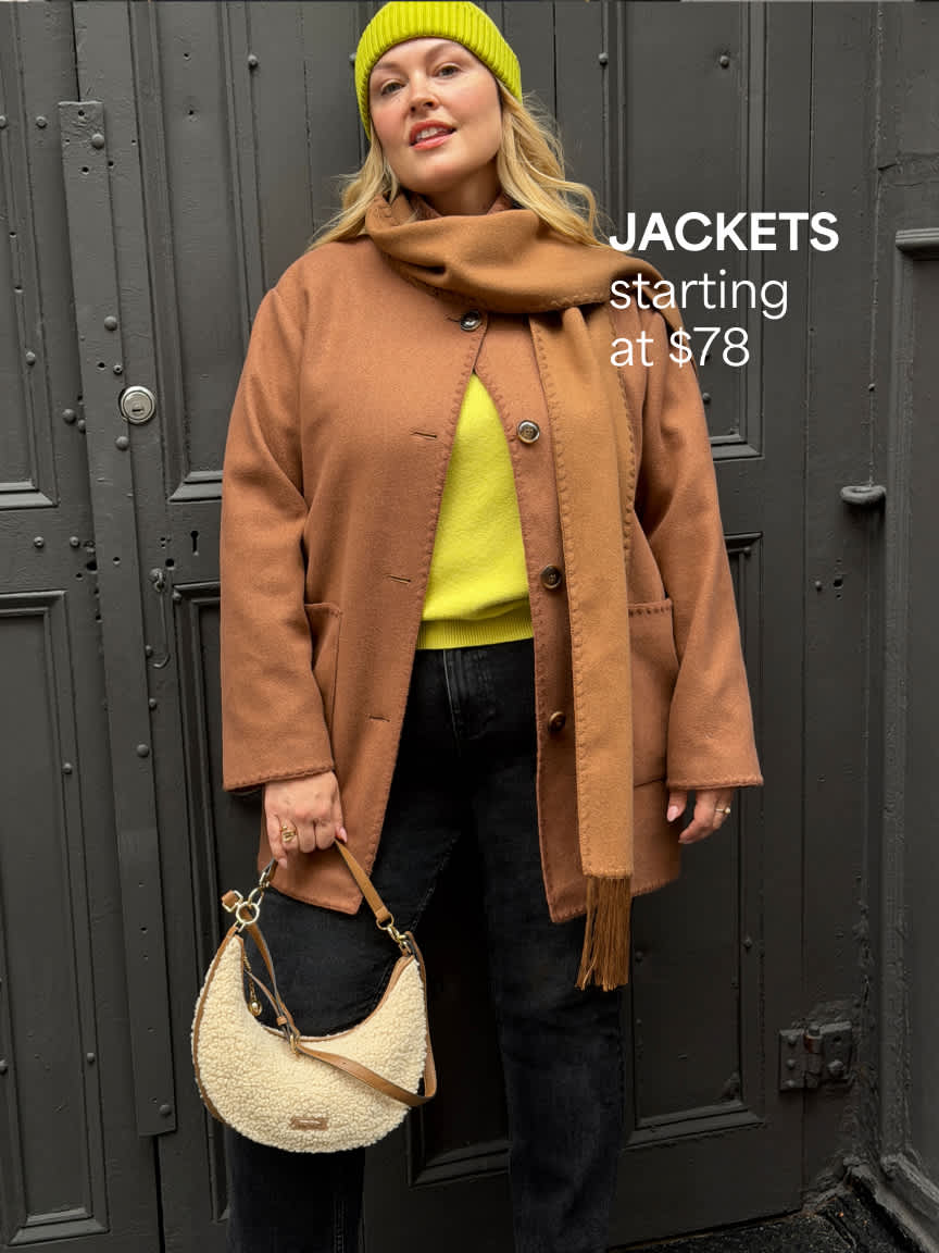 A woman posing in front of dark doors wearing a neon yellow beanie, a bright yellow top layered under a camel brown wool coat with a matching scarf, black pants, and holding a small cream textured handbag. Text overlay reads "JACKETS starting at $78".
