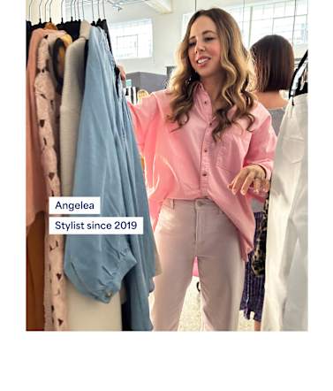 Woman in pink button-up shirt and beige pants browsing rack of blue and neutral tops