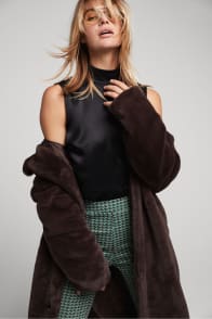 Model in Stitch Fix women’s clothing including a black silk top, patterned pants and faux fur coat.