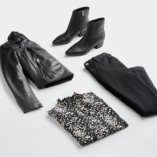 Folded Stitch Fix women’s plus-size clothing including black leather jacket, booties, pants and black and white printed blouse.