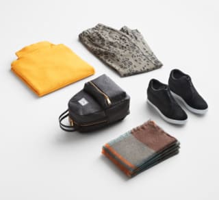 Various plus size athleisure clothing including a yellow top, grey leggings, black backpack and sneakers and a scarf.
