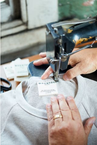 Hands sewing in a Stitch Fix Mohnton Made tag