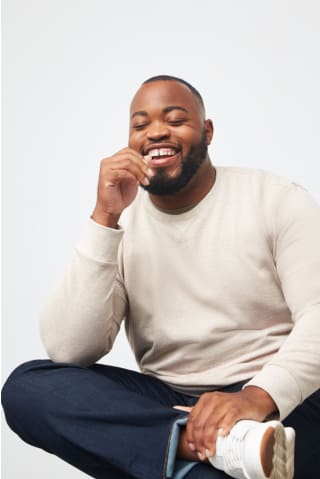 Model wearing Stitch Fix Mohnton Made mens ivory long sleeve shirt with dark blue jeans and white sneakers.