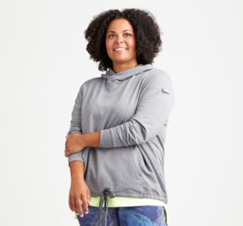Plus size athleisure clothing including a grey hoodie sweatshirt, blue plus size leggings and sneakers.