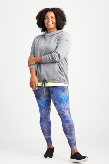 Plus size athleisure clothing including a grey hoodie sweatshirt, blue plus size leggings and sneakers.