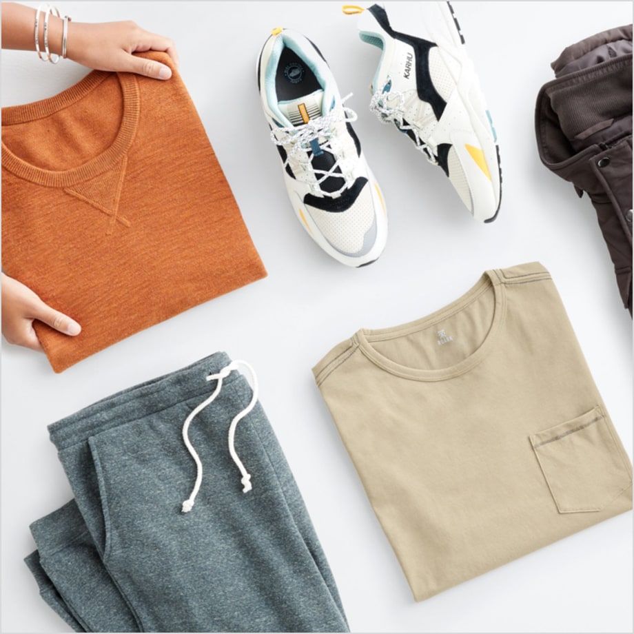 Stitch Fix men’s athleisure clothes including an orange sweatshirt, white sneakers, tan tee and grey jogger pants.