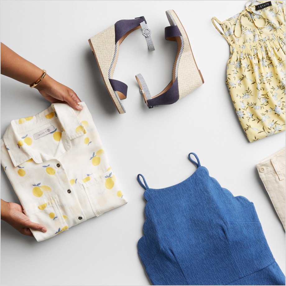 Folded Stitch Fix women’s clothes including yellow and white tops, blue tank and blue sandals.